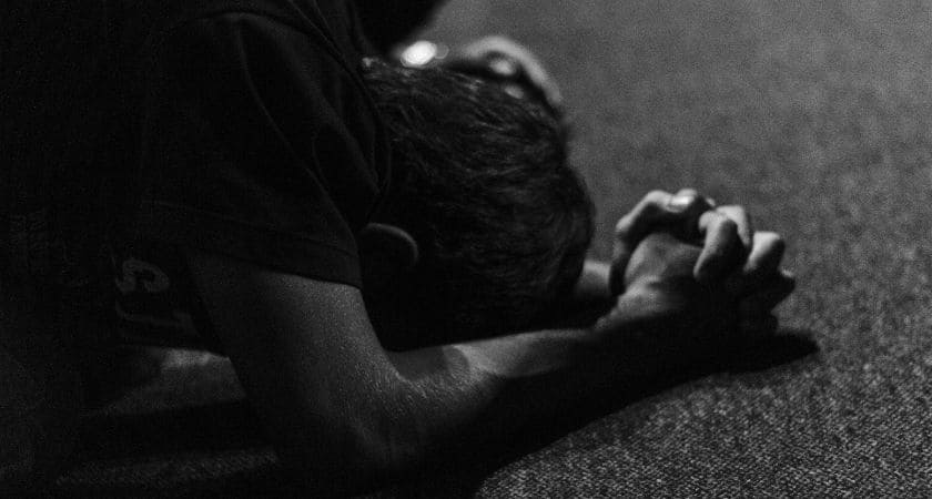 Pessoa orando em silêncio pedindo proteção e livramento, simbolizando fé e refúgio em Deus contra o mal.